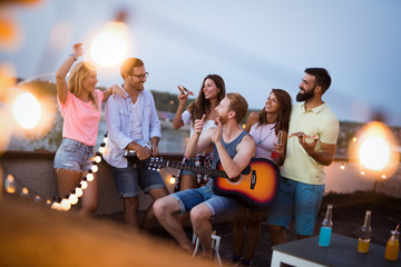 Group of happy friends having party on rooftop
