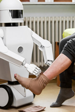 caregiver robot or medical assisted living robot is putting on a compression stocking