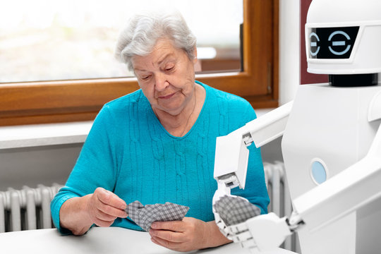 ambient assisted living service robot is playing a card game with a senior adult woman