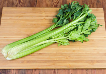 Fresh celery stalks on the cutting board on rustic table