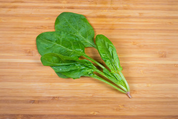 Leaves of fresh spinach on a bamboo wooden surface
