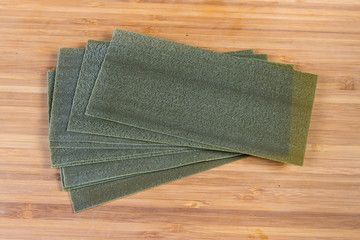 Uncooked green spinach lasagna sheets on the wooden cutting board