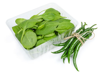 Fresh spinach leaves in plastic container and fresh green chili