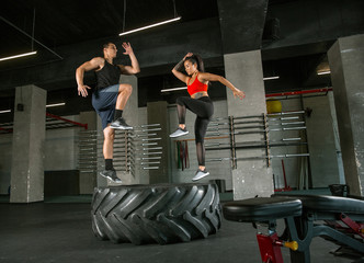 A muscular athletes doing workout at the gym. Gymnastics, training, fitness workout flexibility. Active and healthy lifestyle, youth, bodybuilding. Doing exercises together, training with the tire.