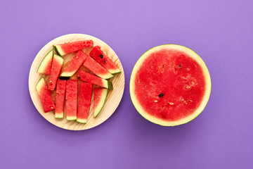 Watermelon cut in half and slices isolated in violet heliotrop background with copy space viewed from above