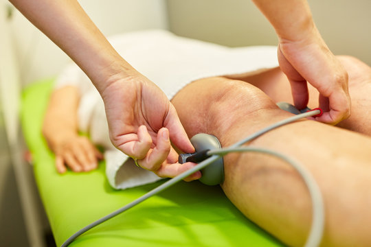 Arzt befestigt Vakuumelektroden am Bein von Patient