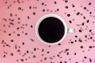 black coffee in a white cup on a pink background levitation of a cup and coffee beans   