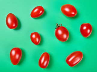 Red cherry tomatoes on green background. Top view.