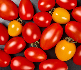 A pile of cherry tomatoes on black background. Texture.