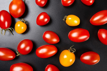 Red and yellow cherry tomatoes on black background. Top view.