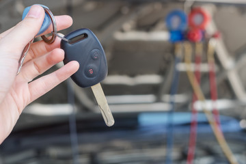 Woman hand holding remote control car key give technician  for check air car system. Mechanic...
