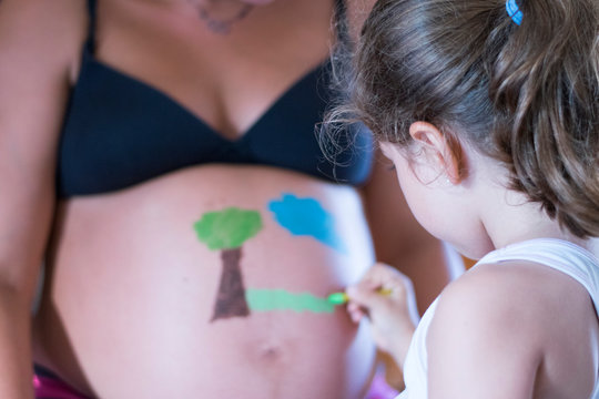 Ni&ntilde;a pintando barriga de embarazada