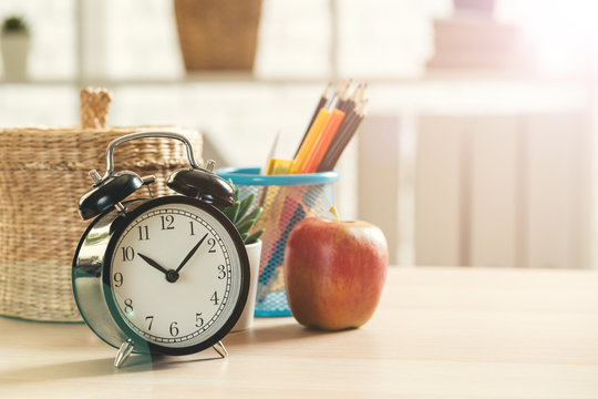 Alarm clock and office stationery objects close up on wooden table