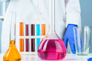 Colored liquids inside lab glassware on white table in laboratory