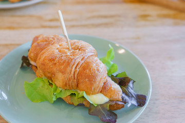 American breakfast set Croissant with ham chess and green oak on blue dish on wooden table background with copy space in morning.