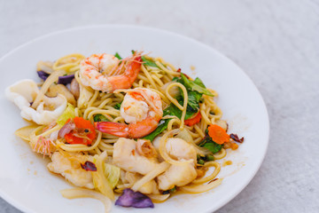 Homemade Spaghetti spicy seafood with prawn and squid on white dish.