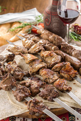 lamb, chicken and pork shish kebab on lavash bread with glass of red wine on wooden table