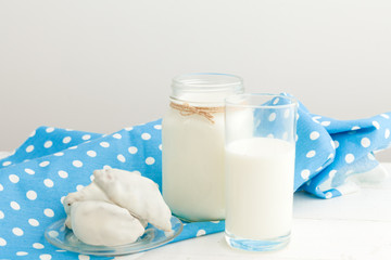 Milk glass and biscuit cookies with kitchen cloth on light background