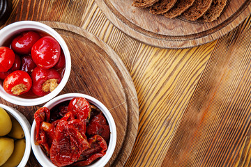 Top view with delicious italian appetizer. sun-dried tomatoes, olives and stuffed peppers in...