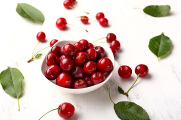 Bowl with ripe sweet cherry on white table