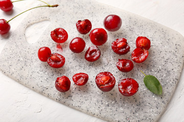 Board with ripe sweet cherry on white background