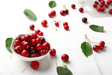 Bowl with ripe sweet cherry on white table