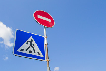 Pedestrian crossing road sign on sky background and red stop sign