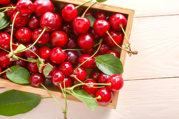 Box with ripe sweet cherry on wooden table