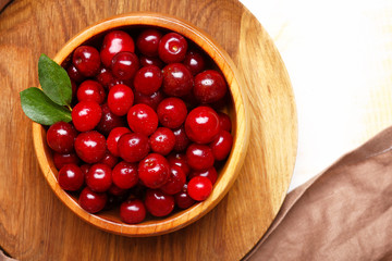 Bowl with ripe sweet cherry on table