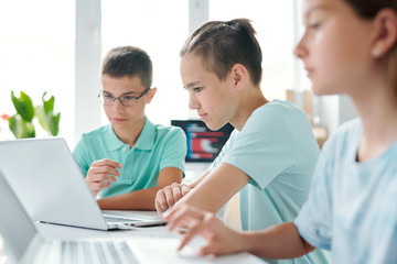 Group of contemporary learners of middle school looking at laptop display