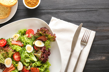 Plate with tasty salad on dark table