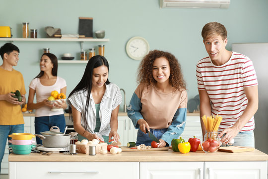 Happy Friends Cooking Together In Kitchen