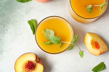 Glasses of tasty peach juice on light background