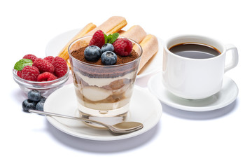 Classic tiramisu dessert with blueberries and raspberries in a glass cup, savoiardi cookies and espresso coffee on white background with clipping path