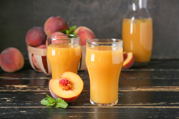 Glasses of tasty peach juice on wooden table