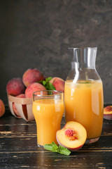 Glass and bottle of tasty peach juice on wooden table