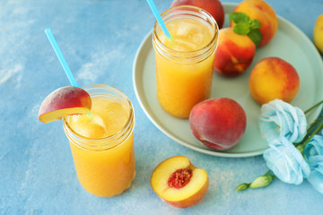Jars of tasty peach juice on color background