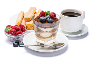 Classic tiramisu dessert with blueberries and raspberries in a glass cup, savoiardi cookies and espresso coffee on white background with clipping path