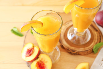 Glasses of tasty peach juice on wooden table