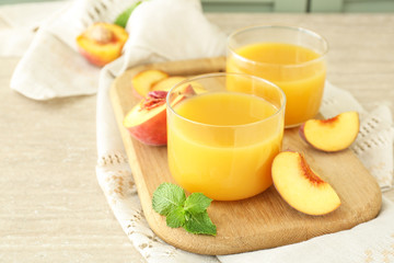 Glasses of tasty peach juice on wooden board
