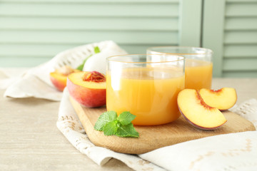 Glasses of tasty peach juice on wooden board