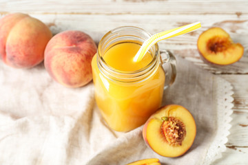 Mason jar of tasty peach juice on table