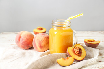 Mason jar of tasty peach juice on table