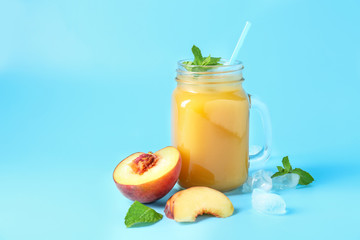 Mason jar of tasty peach juice on color background