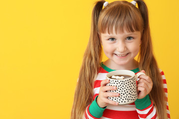 Cute little girl drinking hot chocolate on color background