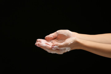 Female hands with soap foam on dark background
