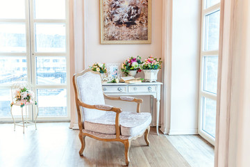 Beautiful luxury classic white bright clean interior bedroom in baroque style with large window, armchair and flower composition