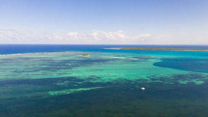 Seascape with coral reefs and islands. Tropical climate and nature of the Philippines. A small island on the atoll.