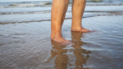 Senior woman's feet are standing on sandy beach, Varicose veins on leg and feet, Asian Body skin part, Healthcare concept