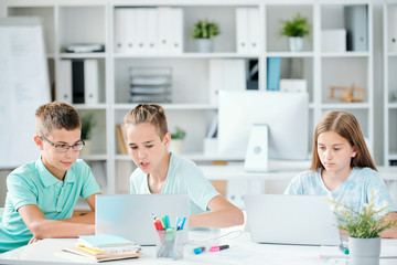 Fototapeta premium One of clever schoolboys showing his classmate curious website